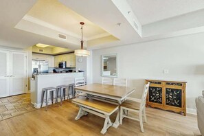 A spacious kitchen with a dining area, white cabinetry, and a wooden dining table. - North Beach Towers 213 (North Myrtle Beach)