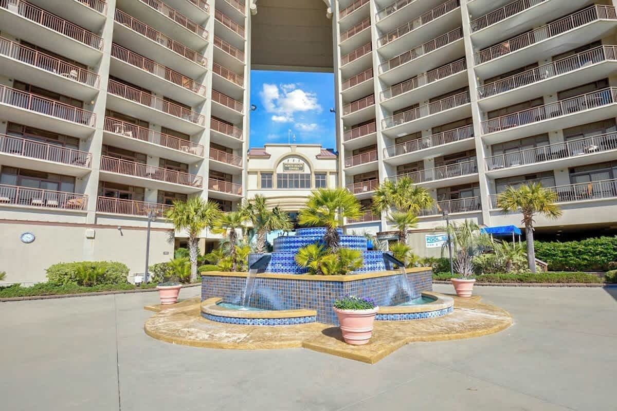 A multi-story hotel with a central courtyard featuring a water fountain, surrounded by balconies.