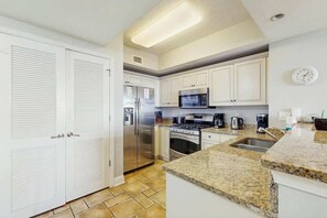 A kitchen with white cabinets, stainless steel appliances, and a granite countertop. - North Beach Towers 213 (North Myrtle Beach)