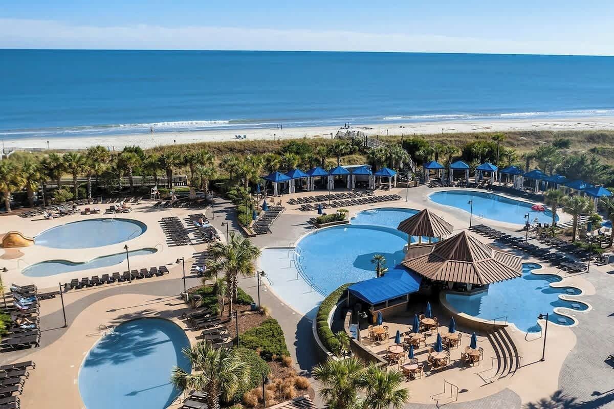 A resort with multiple swimming pools, beach access, and shaded areas.