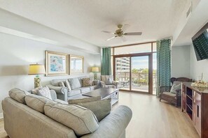 A spacious living room with a sofa set, a coffee table, and a TV mounted on the wall. - North Beach Towers 213 (North Myrtle Beach)