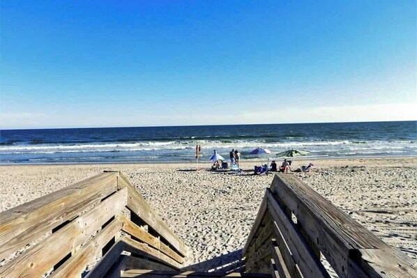 A beach with wooden boardwalks, people relaxing, and umbrellas. - Seaward Villas Unit 5 (North Myrtle Beach)