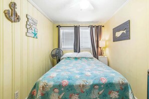 Ein Zimmer mit einem Bett, einem Ventilator, einem Vorhangfenster und Wandgestaltungen.