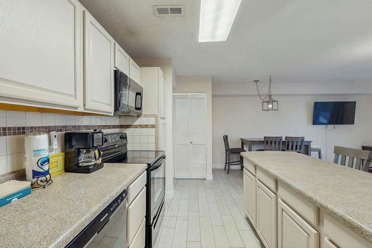 A kitchen with white cabinets, a microwave, a coffee maker, and a dishwasher.