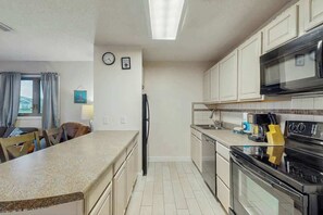 Eine kompakte Küche mit einer zentralen Kochinsel, einer Mikrowelle, einem Backofen und einem Kühlschrank.