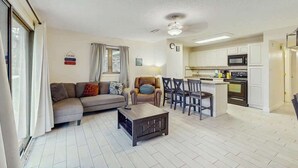 A living room with a sofa, coffee table, and a dining area with chairs and a kitchen in the background. - Eagle Haven H1 Condo (Myrtle Beach)