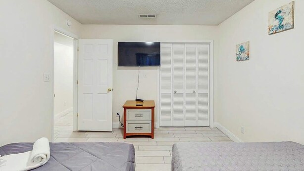 A bedroom with two beds, a TV, a wardrobe, and a small bedside table. - Eagle Haven H1 Condo (Myrtle Beach)