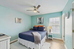 A bedroom with a bed, a ceiling fan, a window with blinds, and a bedside table. - Hawleywood Beach Retreat (Surfside Beach)