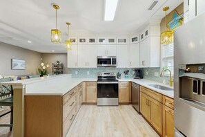A modern kitchen with white cabinets, stainless steel appliances, and pendant lighting. - Hawleywood Beach Retreat (Surfside Beach)