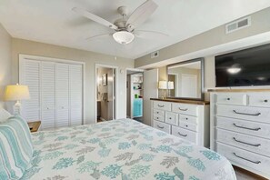 A bedroom with a bed, a ceiling fan, a TV, a dresser, and a closet. - Shore Breeze Unit 2 Condo (North Myrtle Beach)