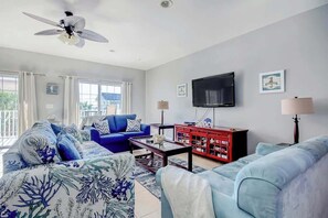 A living room with a ceiling fan, a flat-screen TV, and a red cabinet. - Coconut Grove Unit 203 (North Myrtle Beach)