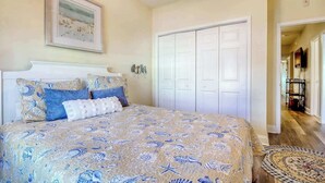 A bedroom with a bed, a wardrobe, and a framed picture on the wall. - Coconut Grove Unit 203 (North Myrtle Beach)