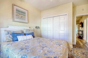 A bedroom with a bed, a wardrobe, and a framed picture on the wall. - Coconut Grove Unit 203 (North Myrtle Beach)