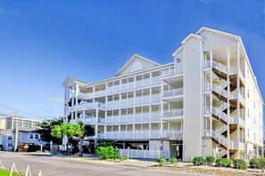 Een hotel met meerdere verdiepingen, balkons, een centrale binnenplaats en een parkeerplaats.