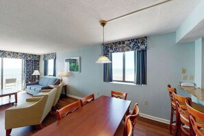 Ein Hotelzimmer mit Essbereich, einer Couch und Blick auf den Strand.