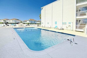 A swimming pool with a clear blue water surface, surrounded by a white building with balconies, and a clear sky above. - Beach Cottages at OD - 33B (North Myrtle Beach)