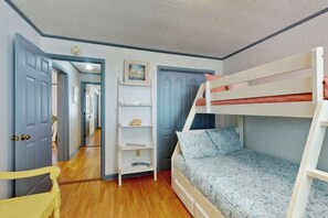 Ein Zimmer mit Etagenbetten, einem weißen Kleiderschrank, einer Tür und einem Flur.