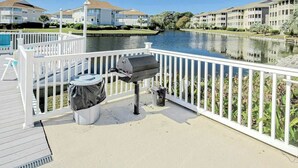 Ein Balkon am Wasser mit Grill, Mülleimer und Liegestuhl am Pool.