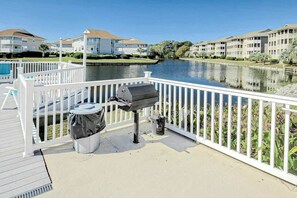 A waterfront balcony with a grill, trash can, and a poolside chair. - Beach Cottages at OD - 33B (North Myrtle Beach)