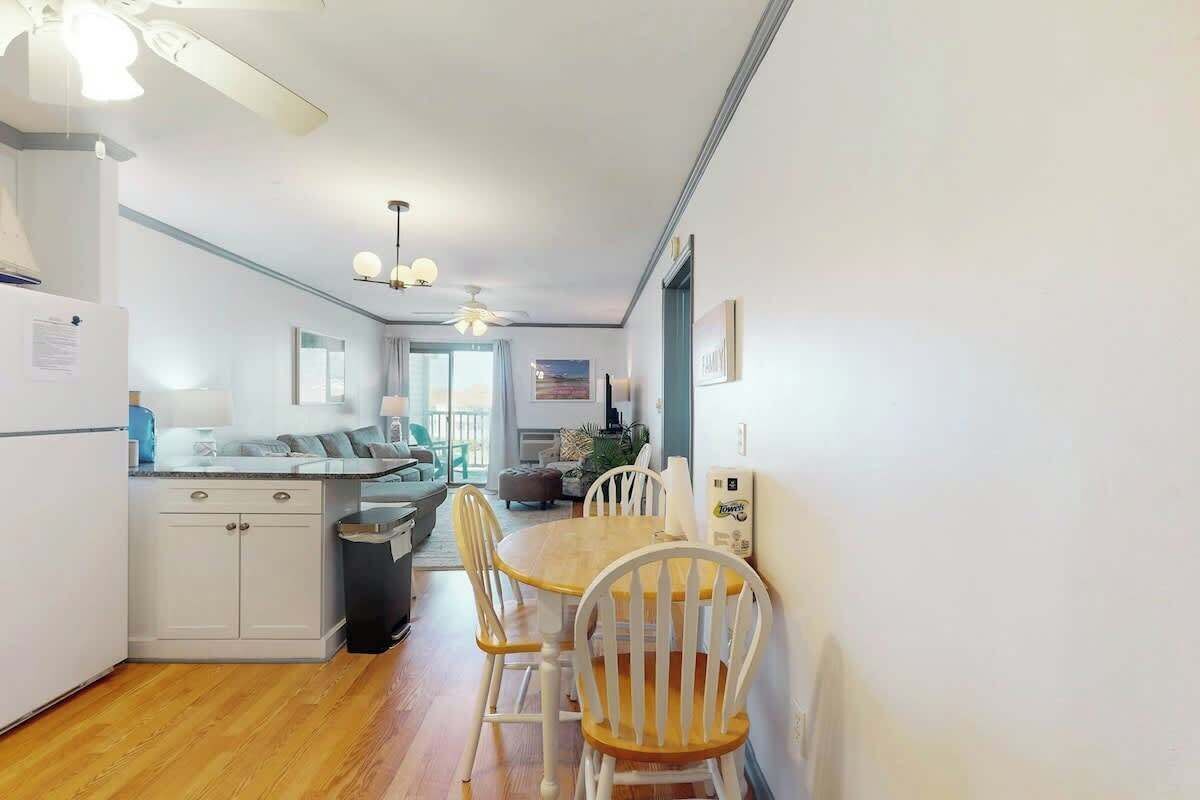 A modern kitchen with white cabinetry, a dining table with chairs, and a ceiling fan.