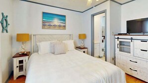 Ein Schlafzimmer mit einem Bett, einem Deckenventilator, einem Fernseher und einem Bild an der Wand.