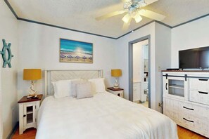 A bedroom with a bed, a ceiling fan, a television, and a painting on the wall. - Beach Cottages at OD - 33B (North Myrtle Beach)