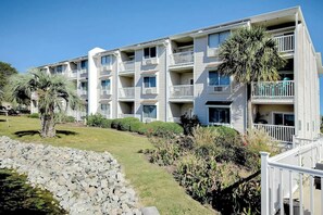 Ein mehrstöckiges Hotel mit Balkonen, einem Swimmingpool und einem gepflegten Garten.