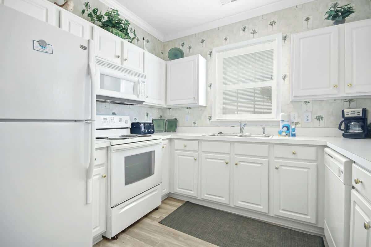A kitchen with white cabinetry, a microwave, a stove, and a window with blinds.