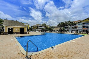 A swimming pool with a lifeguard stand, surrounded by buildings with balconies and a clear sky. - The Havens Unit 1721 (North Myrtle Beach)