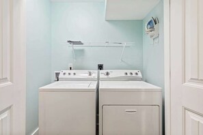 A laundry room with two stacked washers and dryers, a drying rack, and a wall-mounted iron. - Madiera Magic Retreat (North Myrtle Beach)
