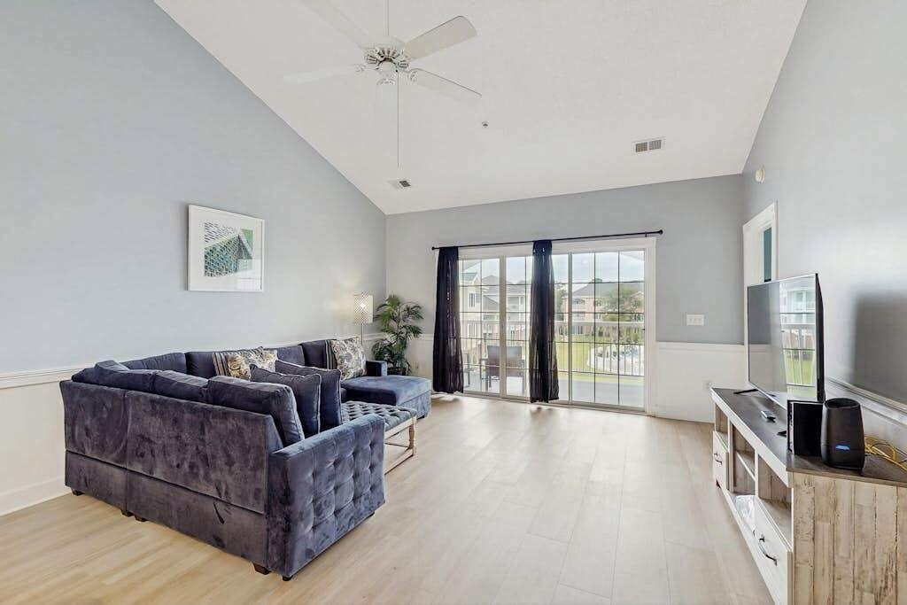 A modern living room with a dark blue sofa, a flat-screen TV, and a ceiling fan.
