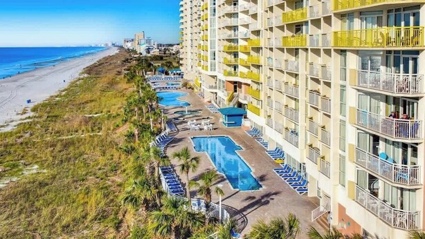 A beachfront hotel with multiple swimming pools, a beach, and a high-rise building with balconies. - Bay Watch Resort 0439 (North Myrtle Beach)