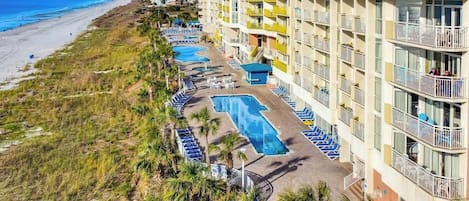 Un hôtel doté de plusieurs piscines, d’une plage et d’un immeuble de grande hauteur avec des balcons.