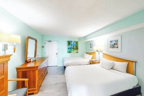 Ein Hotelzimmer mit Bett, Nachttisch, Lampe, Kommode und einer Tür.