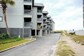 A multi-story building with balconies, a parking lot, and a beachside view. - Cherry Grove Retreat (North Myrtle Beach)