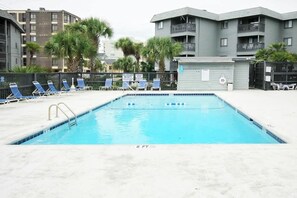 A rectangular swimming pool with a 8 ft depth marker, surrounded by lounge chairs and palm trees. - Cherry Grove Retreat (North Myrtle Beach)