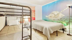 Ein Zimmer mit Etagenbett, Einzelbett und Wandmalerei einer Meeresschildkröte.