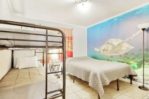 A room with a bunk bed, a single bed, and a mural of a sea turtle. - Cherry Grove Retreat (North Myrtle Beach)
