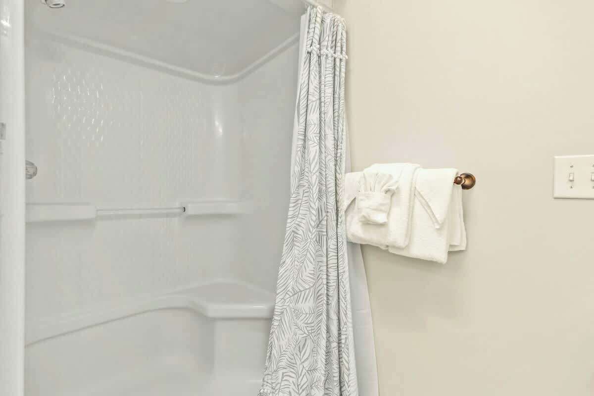 A bathroom with a shower curtain, a towel rack, and a white wall.