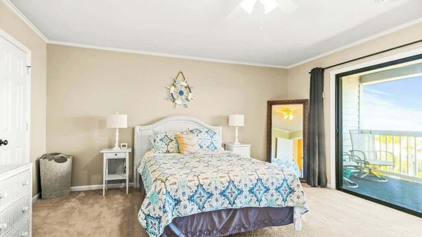 Un dormitorio con cama, mesitas de noche, decoración en la pared y vistas al balcón.