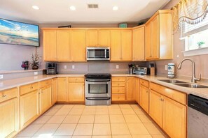 A kitchen with wooden cabinets, a stainless steel oven, a microwave, and a dishwasher. - Waterfront Galore Beach Home (North Myrtle Beach)