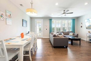 A spacious living area with a sofa, coffee table, and dining table set. - Tidewatch Charms Townhouse (North Myrtle Beach)