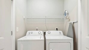 A laundry area with two front-loading washing machines and a drying rack. - Tidewatch Charms Townhouse (North Myrtle Beach)