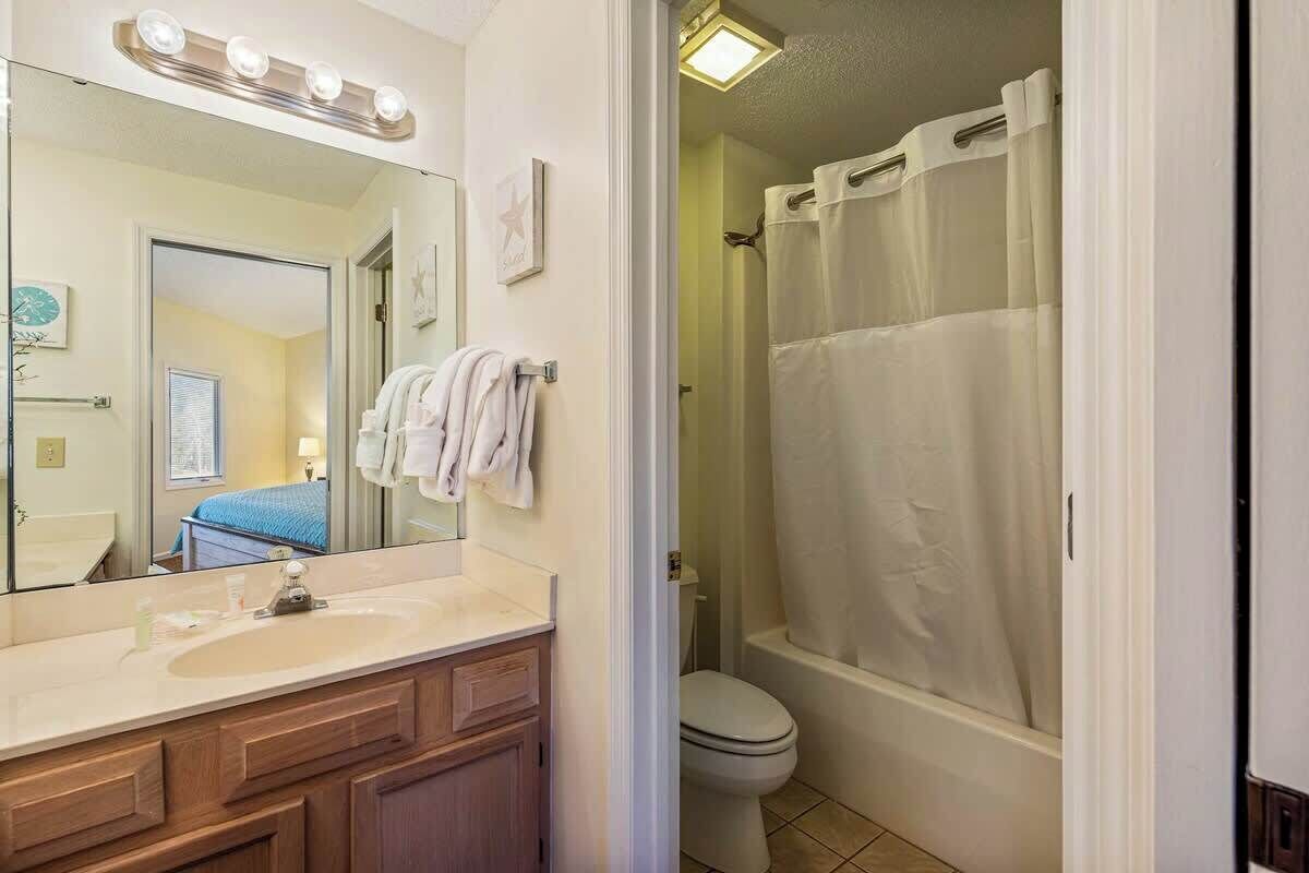 A bathroom with a sink, mirror, and a shower curtain.