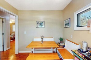 Un comedor con una mesa de madera y bancos, una pequeña planta en maceta y cuadros en la pared.