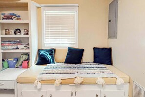 A bedroom with a bed, a window with blinds, a bookshelf, and a desk. - GG's Place Beach House (Atlantic Beach)