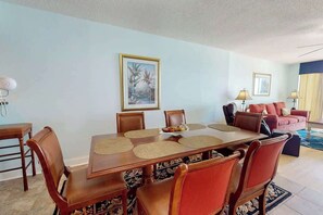 A dining area with a wooden table and chairs, a sofa, and two lamps. - Bahama Sands Unit 0508 (North Myrtle Beach)
