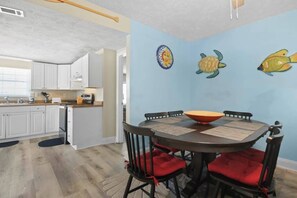 Un comedor con una mesa redonda, cuatro sillas y un muro decorativo con motivos de peces y soles.