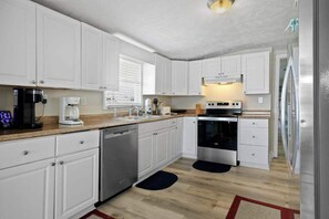 Una cocina moderna con armarios blancos, electrodomésticos de acero inoxidable y una encimera de madera.