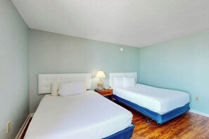 Ein Hotelzimmer mit zwei Betten, einem Nachttisch mit Lampe und Holzboden.